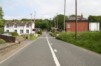 Approaching Dunragit level crossing from the south on 31 May 2007. The rear of the signal box can be seen on the right with the former station building and platform on the left beyond the entrance to the old goods yard.<br><br>[John Furnevel 31/05/2007]