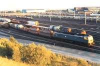 A class 47 at the head of a rake in Mossend yard during a sunny evening in 1989. The Chivas tanks (first two vehicles) are probably destined for Keith.<br><br>[Ewan Crawford //1989]