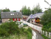 The pedestrian access leading down from the A71 road to West Calder station seen on 21 June 2007 with an Edinburgh Waverley - Glasgow Central via Shotts service standing at the westbound platform. The substantial former station building, part of which can be seen in the picture, is now the <i>Mei Hua</i> Chinese Restaurant.<br><br>[John Furnevel 21/06/2007]