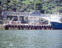 China clay loading in progress at Carne Point, Cornwall, in 1977, near the end of the branch south from Lostwithiel to Fowey Harbour. The pair of class 08 shunters on the wharf alongside the bulk carrier <I>Voreda</I>, (all looking the worse for wear), belong to ECC, having been puchased from BR in 1974.   <br><br>[Ian Dinmore //1977]