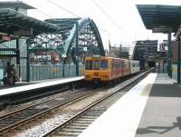 After dropping off two passengers at St Peters, a Tyne and Wear Metro service heads south onto the bridge over the River Wear. The bridge was built in 1879 to bring the lines from the original terminus at Monkwearmouth into Sunderland. Wearmouth road bridge stands on the left of the picture. <br><br>[John Furnevel 10/07/2004]