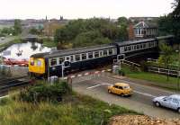 Westbound DMU crossing the (then closed) Forth and Clyde Canal at Swing Bridge East, Falkirk in 1988. The signal box has now gone and the road and level crossing have been replaced with a new road bridge carrying the A9 which was under construction when the photograph was taken (view is from the approach embankment). [See image 20841]<br><br>[Ewan Crawford //1988]