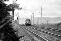 With the Argyll hills in the background a pair of Class 303 units approaches Geilston level crossing, west of Cardross, with an eastbound service in 1974.<br><br>[John McIntyre /03/1974]