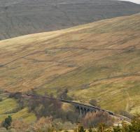 Northbound freight crosses Dent Head Viaduct having just left Blea Moor Tunnel. View from the northern air shaft on the high ground of Blea Moor. Wold Fell and Knoutberry Hill dwarf the train.<br><br>[Ewan Crawford 02/04/2008]