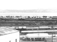 View south over a misty Firth of Tay in May 1980 as a Type 2 hauled Glasgow Queen Street - Dundee service runs past Dundee Central box on the approach to the station.<br><br>[John Furnevel 26/05/1980]