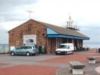 For over 50 years passengers could transfer direct from trains onto coastal steamers at the Harbour station but it closed in 1904. Goods traffic continued until 1933. Now known as the Stone Jetty cafe the sea defences around it have grown considerably in recent years but the building survives and is popular. View across Morecambe Bay to the Cumbrian Coast.<br><br>[Mark Bartlett 17/05/2008]