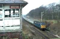 Class 40 No. 40083 on a Blackpool to Euston service passes Weeton cabin, which was perched high on the cutting side to allow a view over the adjacent roadbridge. The box was switched out by this time and later demolished. View towards Singleton and Poulton-le-Fylde in March 1981. [See image 62458] for a <I>Then and Now</I> comparison. Map Ref SD 385338<br><br>[Mark Bartlett 14/03/1981]