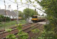 Just before the new Spring foliage makes it impossible, a photograph taken from the site of the down platform at Cleghorn on 15 May with the 1142 Milngavie - Lanark train running over the A706 level crossing as it slows ready to turn off the WCML at Lanark Junction. The former station house stands on the left.<br><br>[John Furnevel 15/05/2008]