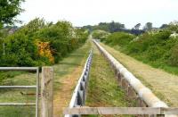 Looking back along the trackbed of the Solway Junction Railway from the remains of the embankment on the north shore of the Solway towards the long closed Annan Shawhill station on 21 May 2008. The waste water pipeline, stretching as far as the eye can see, follows the trackbed through Annan Shawhill and on to Chapelcross. [See image 17151]<br><br>[John Furnevel 21/05/2008]