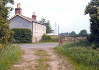 Looking east over the site of the level crossing, complete with surviving gates, towards the former Maxton station on 1 June 2005. The trackbed continues east beyond the fence towards Kelso and Tweedmouth. [See image 59295]<br><br>[John Furnevel 01/06/2005]