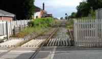 Looking northeast across the level crossing at Midge Hall towards Preston on 24 June 2008. The former station and goods shed stand on the left and the Preston bound platform can still be seen amongst the weeds and vegetation. The Liverpool bound platform was in the undergrowth to the right of the signal post. This former double track main line, once used by Liverpool - Glasgow/Edinburgh express services, has now been split in two, with a DMU operating a shuttle service over the single line between Preston and Ormskirk, where same-platform interchange takes place with Merseyrail electric services.<br><br>[John McIntyre 24/06/2008]