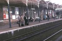 Passengers under the platform canopy at Loughborough Midland await the arrival of an express service in the summer of 1981.<br><br>[Mark Bartlett 15/06/1981]