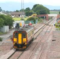 156502, forming the 1107 Carlisle - Glasgow Central, at Dornock on the single line section between Gretna Green and Annan on 17 July 2008, two days before closure of the line in order to complete re-doubling work. The train is approaching the recently renewed junction serving the munitions depot and sidings at MoD Eastriggs, located beyond the security fencing centre left.<br><br>[John Furnevel 17/07/2008]