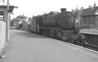 In 1896 the G&SW built a new depot at a rural location near Corkerhill Farm. Because of its remoteness the company built a <I>railway village</I> of 136 houses for workers and families, with a staff halt alongside. Facilities included a general store, wash-house, library, reading rooms, meeting hall, hot baths, allotments and a company doctor. This 1963 photograph shows Black 5 No 45362 reversing east through Corkerhill station towards the signal box controlling access to the shed. On the right is part of the original 1896 <I>railway village</I> on which demolition commenced 6 years later, with the site transferred to Glasgow Council in 1971.<br><br>[Colin Miller 10/08/1963]