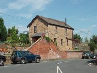 The impressive staircase at this house is the give away that it is the former station entrance. The house was once joined onto and is all that survives of a once large junction station that was swept away soon after closure in 1969. It used to be faced in red brick similar to the stairs and retaining wall. Map Ref SD 509439<br><br>[Mark Bartlett 25/07/2008]