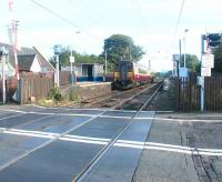 View east over Kingsknowe level crossing in October 2002, with a Glasgow Central - Edinburgh service at the platform.<br><br>[John Furnevel 07/10/2002]