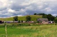 A train for Glasgow passing through the old station at Blackford, the station building can be seen in front of the train. On the hill in the backgpound are the ruins of Blackford Auld Kirk.<br><br>[Brian Forbes 04/08/2008]