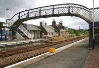 Looking across the tracks towards the southbound (truncated) platform at Lairg on 31 August 2007, just prior to the downpour. The former station building, now in private ownership, stands beyond the large modern platform shelter, with one of the holding tanks of the rail-served Lairg oil terminal, located behind the station, visible just beyond in the background. <br><br>[John Furnevel 31/08/2007]