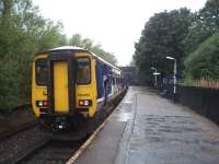 156461 calls at New Hey on the Oldham loop single line section between Shaw and Rochdale. View towards next stop Milnrow and the train will then go on to Manchester before going out to Kirkby or Southport. The guard leans out for a pre departure check on a very wet day. All original station buildings [See image 21081] were long gone at New Hey and on this day the platform shelter was under water. The station closed in October 2009 for conversion to Metrolink tram operation and reopened in 2013.<br><br>[Mark Bartlett 30/09/2008]