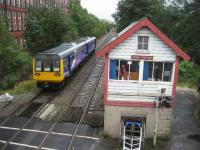 A stopping service to Manchester Victoria departs Shaw and Crompton over the level crossing. The lower half of the L&YR signal box has clearly undergone some running repairs over the years looking at the breeze blocks. No doubt an alternative method of crossing control will arrive with the trams after 2009.<br><br>[John McIntyre 30/09/2008]