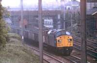 Coal for Fleetwood Power Station, probably from Bickershaw or Golborne Colliery, trundles through Leyland in an unfitted train on the down fast line behind a split headcode Class 40 in 1981. In the background, wagons can be seen parked on the down slow in the station while the train engine shunts the goods yard. [See image 21230]<br><br>[Mark Bartlett /04/1981]