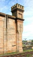 A surviving castellated tower at the north east corner of Greenock Central that once provided part of the support for the former station roof (note the 'slot' in the wall). Photographed in July 2005 looking out across the station's east end bay with another famous Clydeside structure standing on the horizon.<br><br>[John Furnevel 29/07/2005]