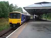 View towards Wigan along the island platform at Atherton as 150135 leaves for Southport in September 2008. The booking office and connecting footbridge can be seen in the background. The former outer platforms are however completely hidden beneath undergrowth and trees. <br><br>[Mark Bartlett 30/09/2008]