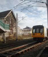 The former station building at Hest Bank, closed in 1969, still sits on the Up line next to the level crossing and is used as business offices although the platforms were removed for electrification. The bridge steps in the picture provide a useful vantage point for the down line but 142095 is seen here from the lineside fence as it slowly joins the main line from the Bare Lane link line.<br><br>[Mark Bartlett 05/03/2010]