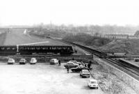 Following the withdrawal of passenger services on the BR Rochdale - Bury (Knowsley Street) - Bolton route in 1970 a single line remained in use for those trains still serving Rawtenstall coal concentration depot. These trains used the Knowsley Street - Bolton Street curve to access the branch. When the new Bury station was opened in 1980 the rerouted line into the new terminus not only crossed the freight line on the level, but cut through the former platforms of the abandoned Knowsley Street station. In this photograph, looking east on 14 February 1981, a 504 EMU has just left the new Bury station and is about to run south over the crossing on its journey to Manchester Victoria, while in the background a DMU awaits its turn to cross westbound with a railtour heading for Rawtenstall. An ELR bridge with a pronounced hump now spans the Metrolink tracks at this location [See image 24666] and the area in the foreground has a multi-storey car park. <br><br>[Mark Bartlett 14/02/1981]