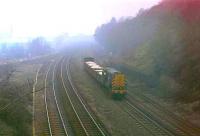 With that self important air that all diesel shunters seem to have when on the main line, Class 08 No. 08574 growls into Horbury cutting with five open wagons of sand. The station, closed in 1970, was by the bridge in the mist with Healey Mills yard just beyond. The line going off to the left went to Crigglestone and then Barnsley but closed in 1991. This is a former mystery picture and David Pesterfield identified the location but we also asked about the sand traffic? Was it a regular trip or a one off? We presumed it originated in Healey Mills yard and, with a 15mph shunter and open wagons, that it was not going far, but where...? [See image 24519] for the answer with thanks to Bill Jamieson and Wyn Garnett, a former Healey Mills shunter.<br><br>[Mark Bartlett 10/04/1979]