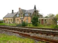 Known in the past for its sulphurous spa waters, the village of Gilsland stands alongside Hadrians Wall, straddling the border between Northumberland and Cumbria. The station was first opened in 1836 as Rose Hill but became Gilsland in 1869. Passenger services were eventually withdrawn in 1967. The photograph, taken looking north across the Newcastle & Carlisle line  in May 2006 from the car park of the Station Hotel, shows the former main waiting room on the left with the booking office and station masters house in the centre. Note the arched ticket window and the old platform drinking fountain still in place. [See image 37929]<br>
<br><br>[John Furnevel 06/05/2006]