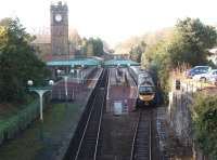 A Manchester Airport service, on time at 12 noon, with 185129 leaves Ulverston station with its restored building and canopies. The cars on the right are in a dealership that occupies the old Furness Railway terminus station [See image 22211]. View west towards Barrow-in-Furness.<br><br>[Mark Bartlett 17/01/2009]