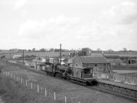 A peaceful rural scene looking west over the former Ormiston station, East Lothian, towards Smeaton Junction from the B6371 road bridge around 1964. Ivatt class 2MT 2-6-0 no 46462, off St Margarets shed, a regular on the branch freight, pauses at the platform with a brake van. By this time the station had been closed to passenger traffic for over 30 years, but the branch remained open for freight until 1965.<br><br>[Robin Barbour Collection (Courtesy Bruce McCartney) //1964]