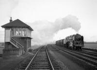 Standard Class 9F 2-10-0 no 92233 powers a freight north past the loops at Quintinshill in November 1964 as the signalman looks out from the open window of Quintinshill signal box.<br><br>[Robin Barbour Collection (Courtesy Bruce McCartney) 28/11/1964]