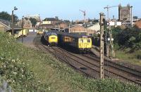 The scene at Colchester St Botolphs around 7 a.m. on Friday June 20th 1980. The Class 308 EMU local service to Clacton is drawing out past 37 259, which is waiting to leave with a permanent way train it has turned via the nearby triangular junction. At left is Colchester National Carriers Depot, a once busy rail-road transhipment facility that would close within weeks and be flattened a year later.<br><br>[Mark Dufton 20/06/1980]