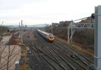 A Pendoline speeds south past the still well used loops, and <I>double slip crossing</I> points at Carnforth in February 2009. On the left a small platform can be seen. This was Crag Bank Halt and was used for the steam shuttle passenger services when Steamtown was still open to the public. West Coast Railway Company stored stock can be seen in the private sidings and the old coaling tower stands beyond. <br><br>[Mark Bartlett 13/02/2009]