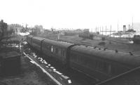 Looking towards Gourock station in February 1966 with e.c.s. coming in, having been stabled somewhere popular with seagulls. A 2-6-4T is at the water column on the extreme right, an ABC Class Ferry is on the Dunoon service and DEPV Talisman (in her final operational year) is on the wires. Just in front of the ferry's bow can be seen the oil tank wagons used to deliver fuel to the ships. The white objects lying alongside the main line are components for the cls cable troughs being installed at that time.<br>
<br><br>[Colin Miller /02/1966]