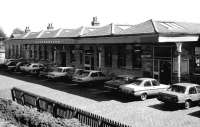 A fine collection of period saloons, complete with proper boots, occupies the cobbled station car park at Dunfermline in 1985. Despite removal of the redundant letters, the station's former name can still be clearly made out in the two-tone paintwork above the main entrance. This became the sole station in Dunfermline between the closing of Dunfermline Upper in 1968 and the opening of Dunfermline Queen Margaret in 2000. Inexplicably, for a short time during the 1990s, it was referred to once again as Dunfermline Lower in timetables and a road sign appeared nearby directing drivers to <I>Lower station</I> [see image 17460].  Equally inexplicably, the current dot matrix departure screens in the area refer to it simply as 'Dunfermline' rather than 'Dunfermline Town'.<br>
<br><br>[David Panton /05/1985]