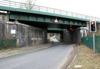 Two bridges on a former 4-track section of the WCML over the B5239 at Standish, with the bricked up arch between once giving access to Standish station (closed 1949). What might appear at first glance to be graffiti plugging a new rock band has been put there to identify the bridge carrying rail traffic for reporting purposes in the event of a bridge strike. The other, out of use, bridge has some severe indentations, suggesting that the road vehicles involved may have needed major surgery! [See image 22604]<br>
<br><br>[John McIntyre //]