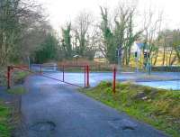 View west along the trackbed of the Penicuik Railway about a mile short of the terminus in February 2009. The line has just entered the town at this point and, on the right beyond the second gate, where the information board is now located, stood the wooden platform of Eskbridge station, closed in 1930. The branch lost its passenger service completely in 1951 but remained operational until 1967, thanks to the freight traffic generated by the remaining paper mills along this part of the Esk. Part of the bridge over the river from which the station took its name can just be seen on the right of the picture, recently reduced to single lane traffic controlled by lights. <br>
<br><br>[John Furnevel 22/02/2009]