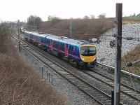 Transpennine Express 185145, heading north, passes Freightliner 66595 and an infrastructure train in the down loop at Oubeck, just south of Lancaster. The stones on the cutting side mark the site of a previous landslip. <br><br>[Mark Bartlett 11/03/2009]
