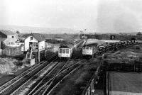 Class 25 Bo-Bo No. 25153 has set its train of ballast wagons back onto the West to South chord at Burscough Bridge to allow a Derby Class 108 DMU to pass on its way to Southport. The main line is protected by catch points and the small ground shunting signal or <I>dolly</I>. The chord was still in occasional use at this time to access an MOD Depot at Burscough Junction. The Preston to Ormskirk line can be seen in the background crossing the Wigan line and the formation of the West to North curve starts just behind the signal box. [See image 22976] for a <I>Then and Now</I> comparison. <br><br>[Mark Bartlett 03/11/1980]