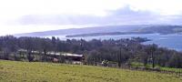 As the <I>great Network Rail tree massacre</I> heads north, new photo opportunities are opening up and the tourists will be rewarded with some good views.  A Class 66 passes above the Rhu narrows on 25 March with a train of tanks.<br><br>[John Robin 25/03/2009]