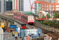 View east from the end of platform 4 at Poplar station on the Docklands Light Railway in July 2005. The train is on the flyover heading for Canning Town, crossing over the lower level route, which is about to turn north towards Devon's Road and on to Stratford. Below left stands part of the DLR's Poplar maintenance depot and stabling sidings. Much of the surroundings still has the feel of a massive building site.<br><br>[John Furnevel 21/07/2005]