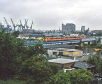 An emu runs through Partick in the 1990s. Scotway Haulage and the Meadowside Granary are now gone as is the scrapyard in the foreground which has been flats for many years.<br><br>[Andy Kirkham //]