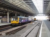 The trainshed at Huddersfield sees 142042 and 158902 on a centre road between turns whilst through trains go on the opposite side of the island platform. This picture looks north from outside the <I>Head of Steam</I> buffet bar, which, in addition to being on the Rail Ale trail, has a remarkable collection of nameplates, number plates, station signs and pictures.  <br><br>[Mark Bartlett 04/04/2009]