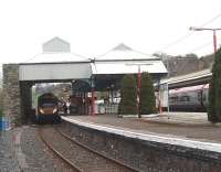 Branch line connection made. Windermere bound Transpennine unit 185143 waits under the trainshed at Oxenholme as a Pendolino stops in the Up line platform. The Windermere branch drops down to Kendal from the junction before its scenic climb to the terminus.<br><br>[Mark Bartlett 09/04/2009]