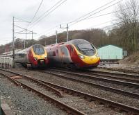 As 390008 leaves Oxenholme for Euston a Voyager stops, on its way to Scotland, to connect with the Windermere branch train. The line in the foreground is the branch connection with the down line. The camber of the main line tracks as they curve through the station can clearly be seen. <br><br>[Mark Bartlett 09/04/2009]