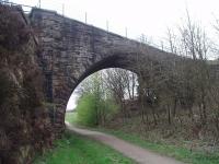 A remarkable bridge with an interesting story.  Built to carry the Lee Moor Colliery tramway across the Bacup to Rochdale line the bridge is straight and steeply graded but the arch is skewed. The footpath shown is about fifteen feet above the level of the old trackbed so before this infilling the arch was evenmore impressive. The line closed in 1947 but remained in situ for many years and the bridge featured in a scene in the film <I>Whistle Down the Wind</I> made in the early 1960's, as did nearby Newline Tunnel [See image 23530]. View down the gradient towards Bacup.<br><br>[Mark Bartlett 16/04/2009]