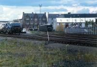 A view looking to the buffer stops at Bathgate Goods Yard. At this date the yard was used to store and unload freight trains carrying new cars. This yard was located to the south of the 1986 terminus. The line to Airdie had been lifted only a few years before and its trackbed was still in very good shape. This ran off to the left in the foreground. Bathgate Upper station was off to the left. The site of the yard is now occupied by various retail outlets. The station can be seen on the right hand side. The station was fitted with an attractive screen to spare delicate passengers from the view of the goods yard.<br><br>[Ewan Crawford //1988]